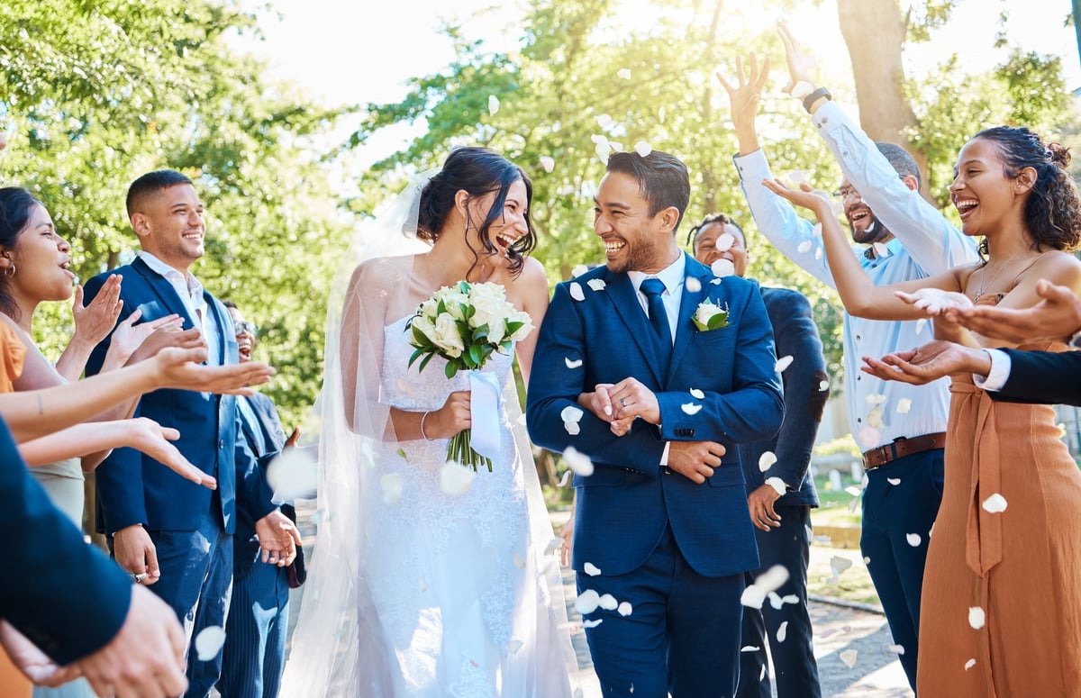Wedding guests throwing rose petals confetti tradition over bride and groom on their special day.