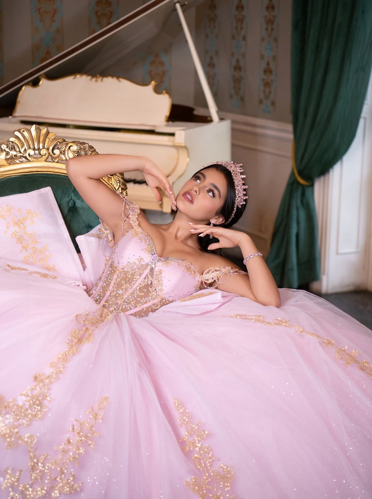 Woman in pink and gold ball gown reclining on a chair by a grand piano in an elegant room